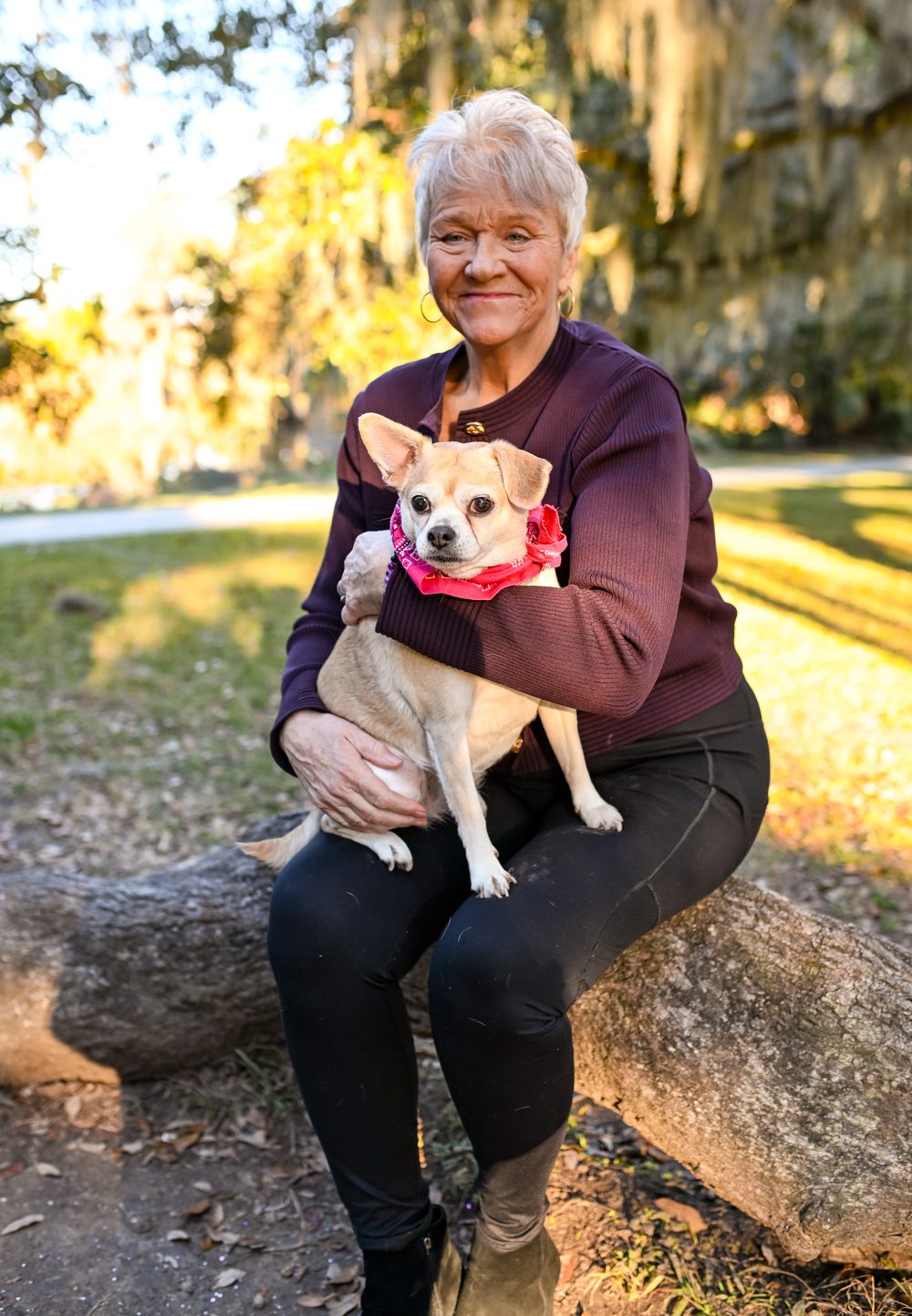 Linda Williams sitting outdoors holding her small dog